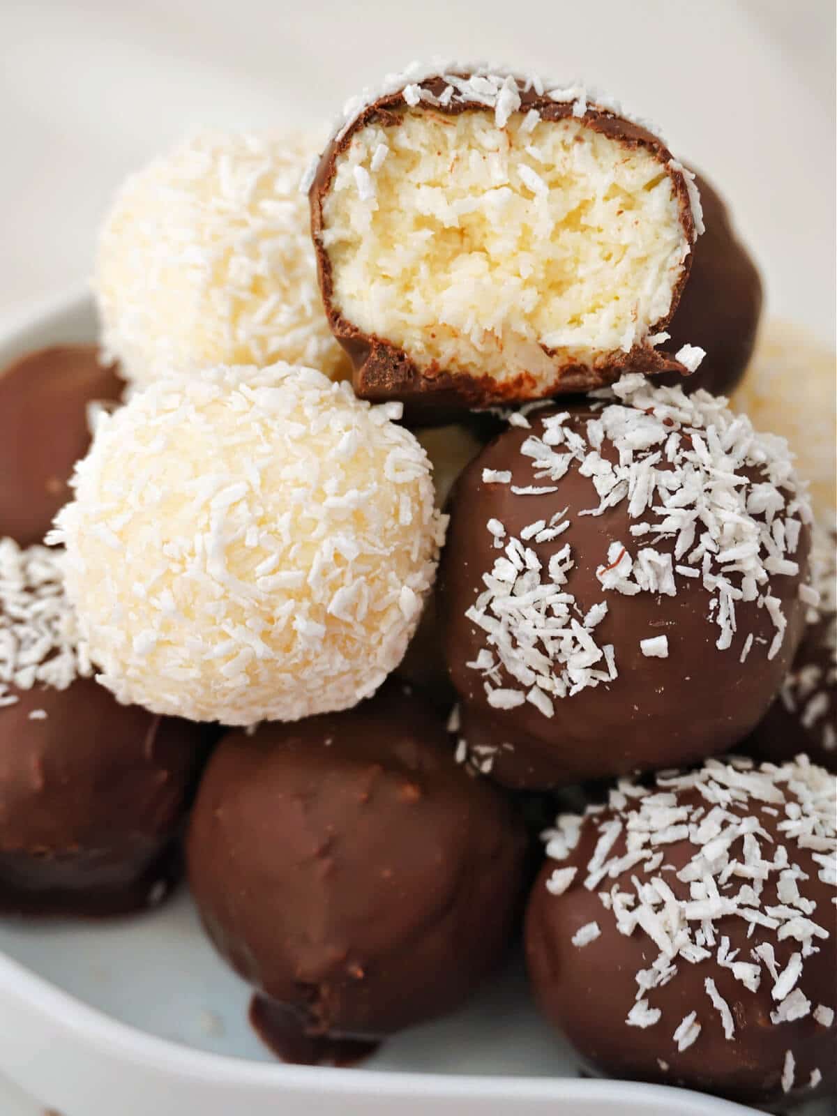 A pile of coconut truffles on a white bowl