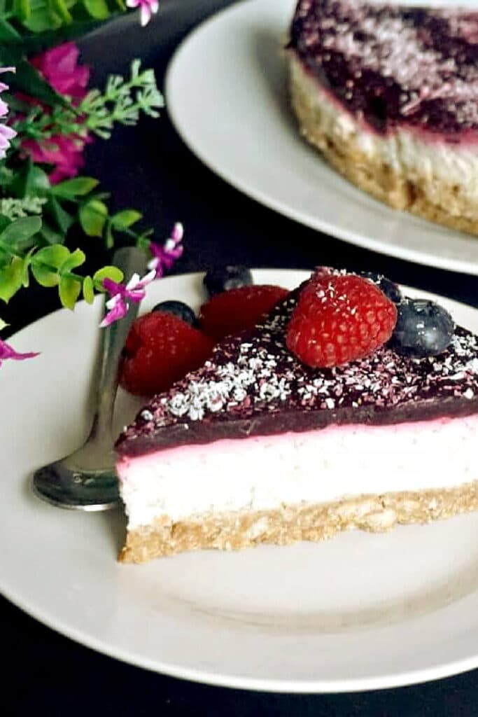 A slice of coconut cheesecake topped with berry jelly and fresh berries