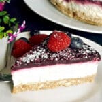 A slice of coconut cheesecake with berries on a white plate