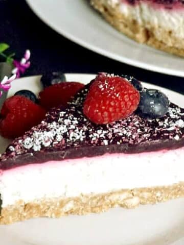 A slice of coconut cheesecake with berries on a white plate