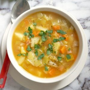 Overhead shoot of a white bowl with leek and potato soup and a spoon next to it