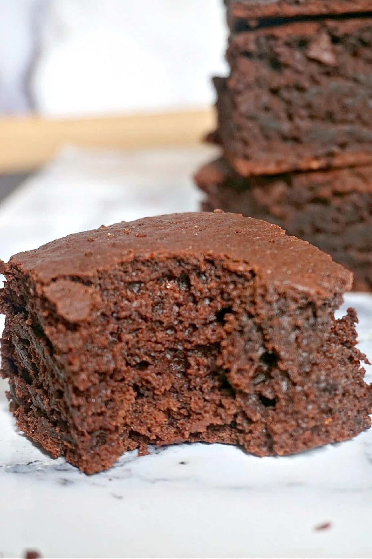 A half a brownie with more brownies in the background.