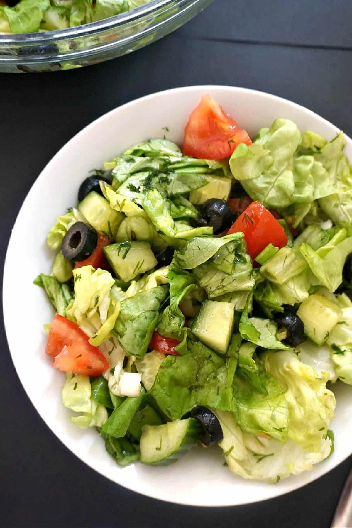 A white bowl with green salad.