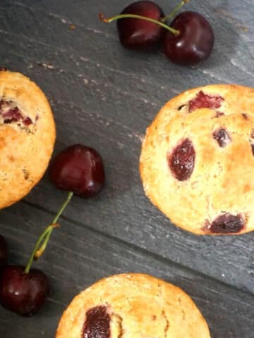 Overhead shoot of 3 cherry muffins with cherries around them