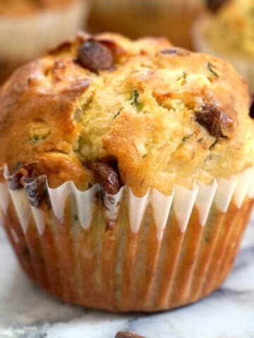 A courgette muffin with chocolate chips on a table top