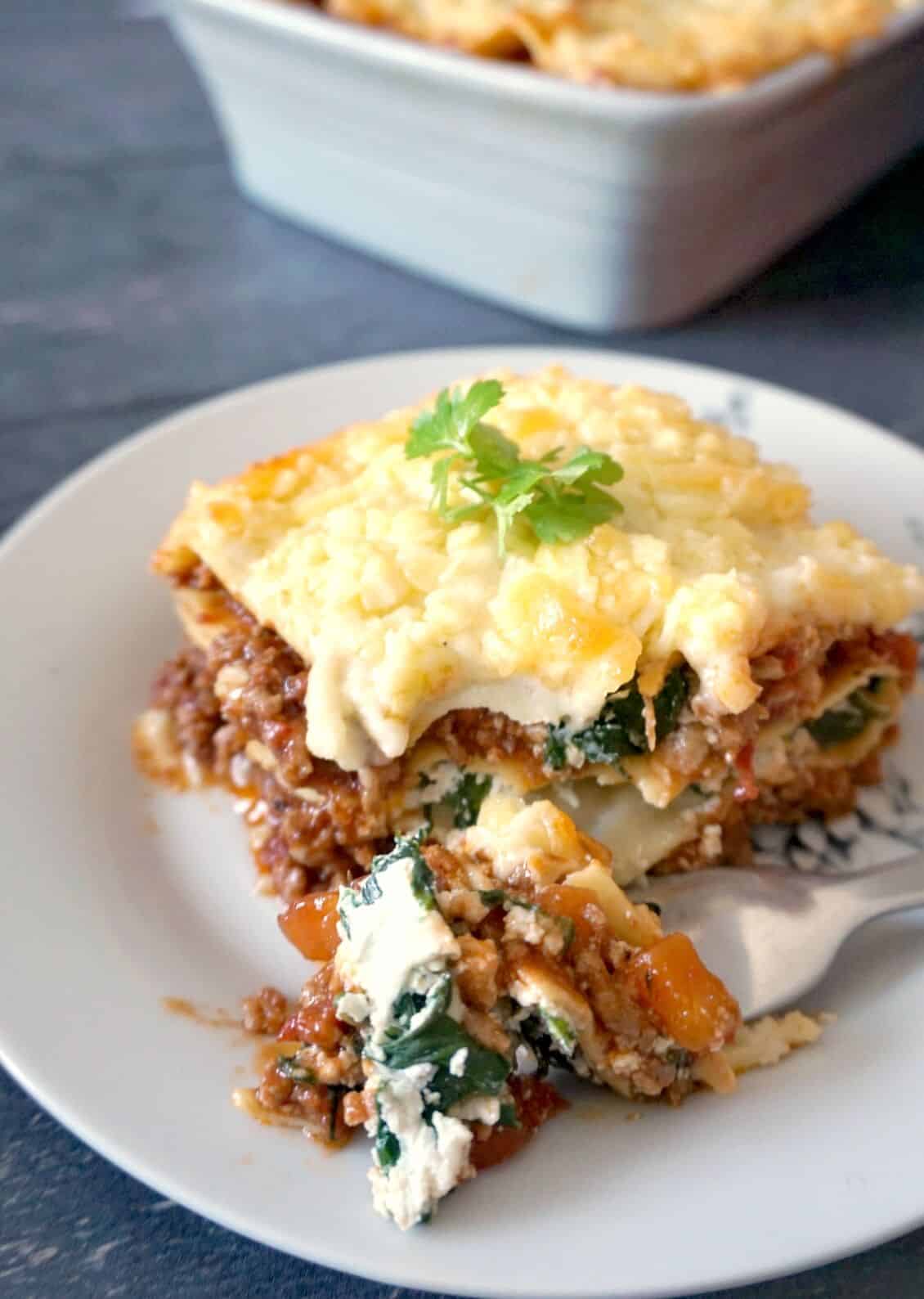 A fork taking a bite of a lasagna slice.