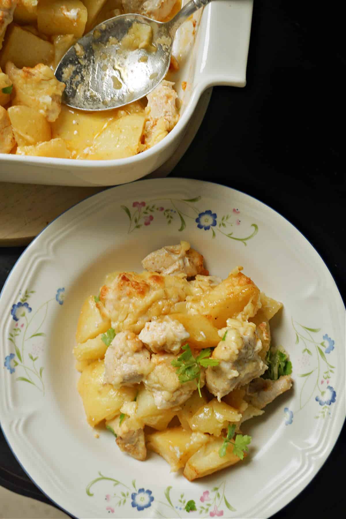 Overhead shoot of a white plate with chicken and potato bites, and a dish at the top with more food.