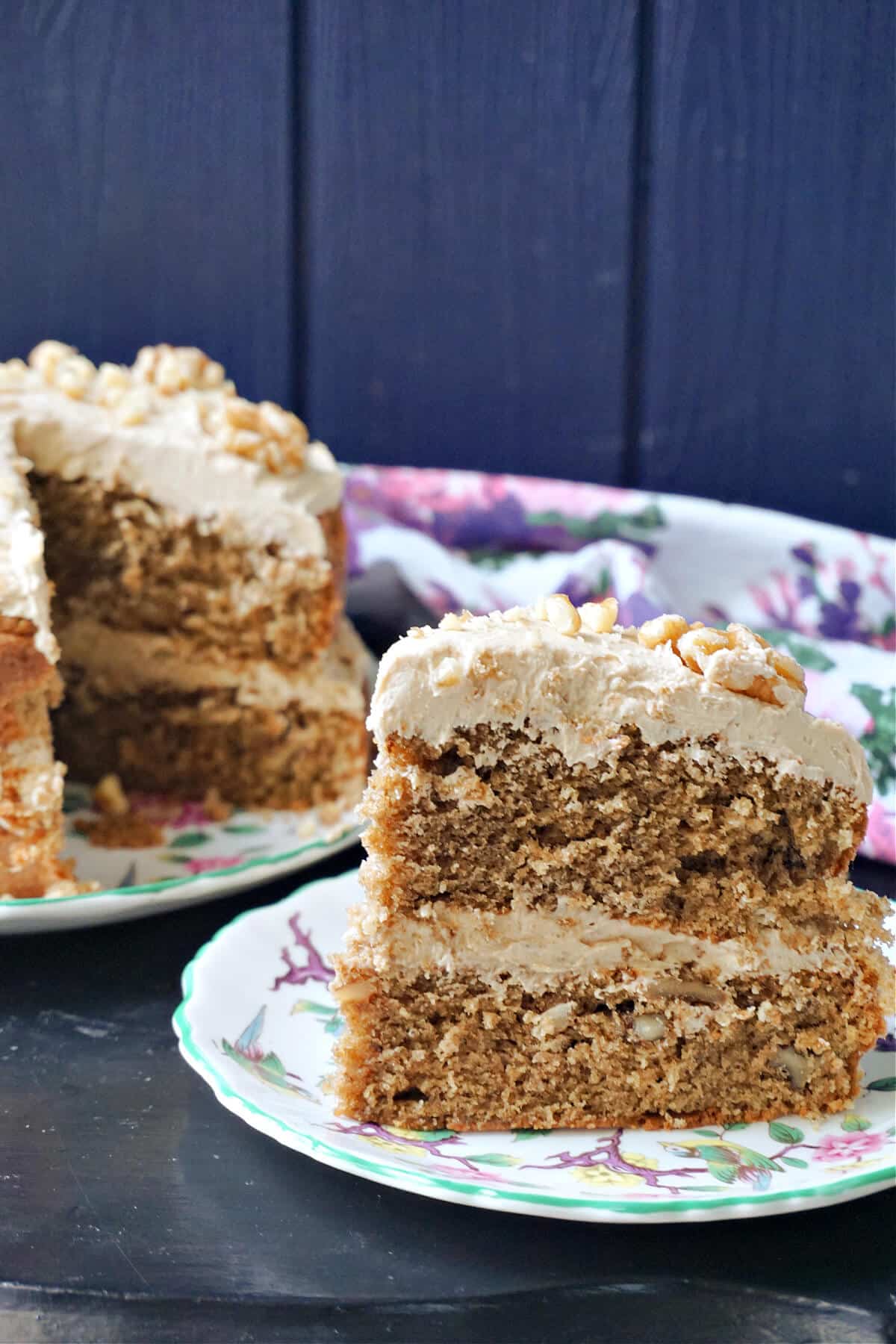 A slice of a cake on a plate with more cake in the background.