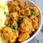 A white bowl with rice and chicken curry