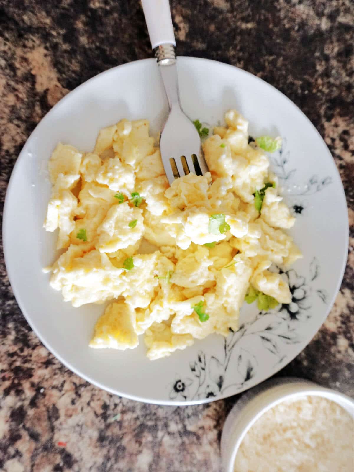 Overhead shot of a white plate with scrambled eggs.