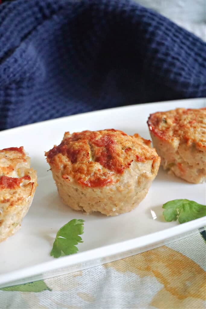 A white rectangle plate with 3 meat mini muffins.