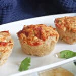 A white rectangle plate with 3 meatloaf muffins and parsley leaves around.