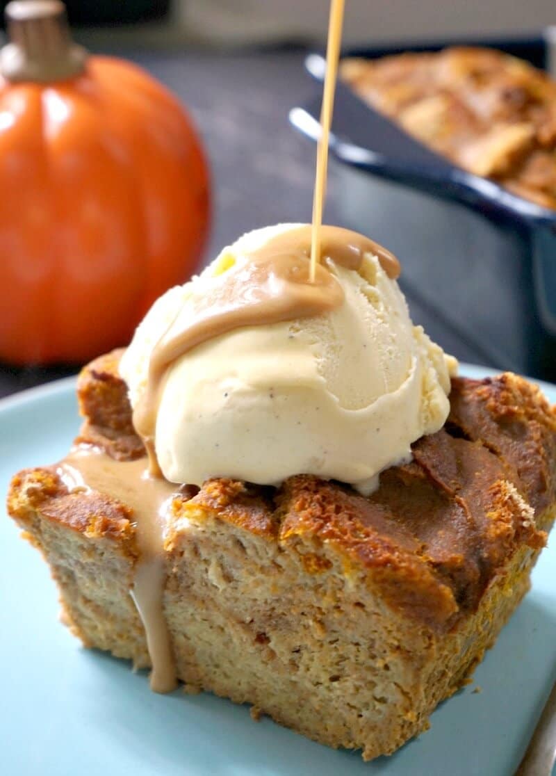 A slice of pumpkin bread pudding topped with an ice cream scoop and butterscotch sauce.