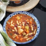A blue bowl with minestrone soup