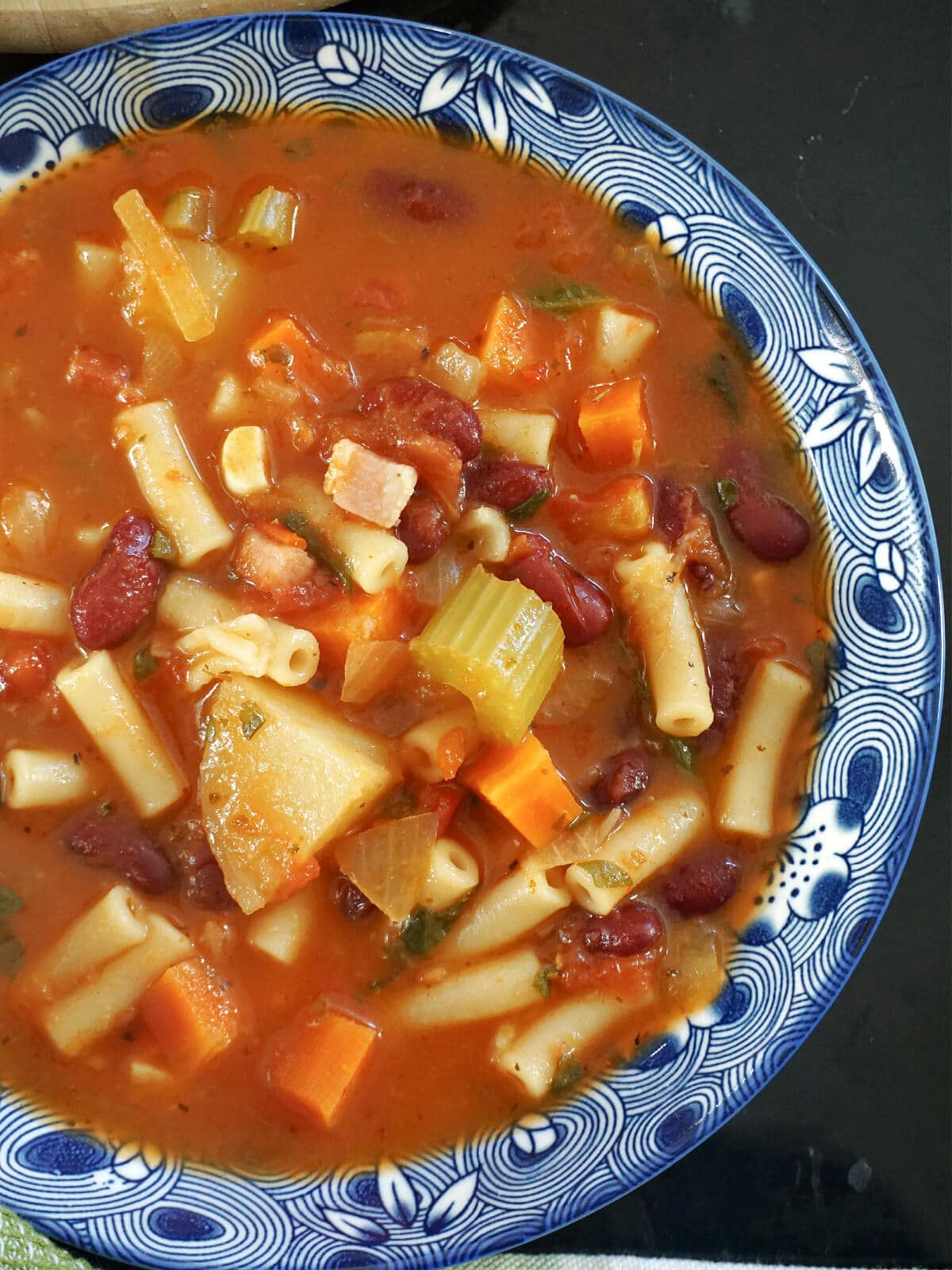 Close-up shoot of a blue bowl of minestrone soup.