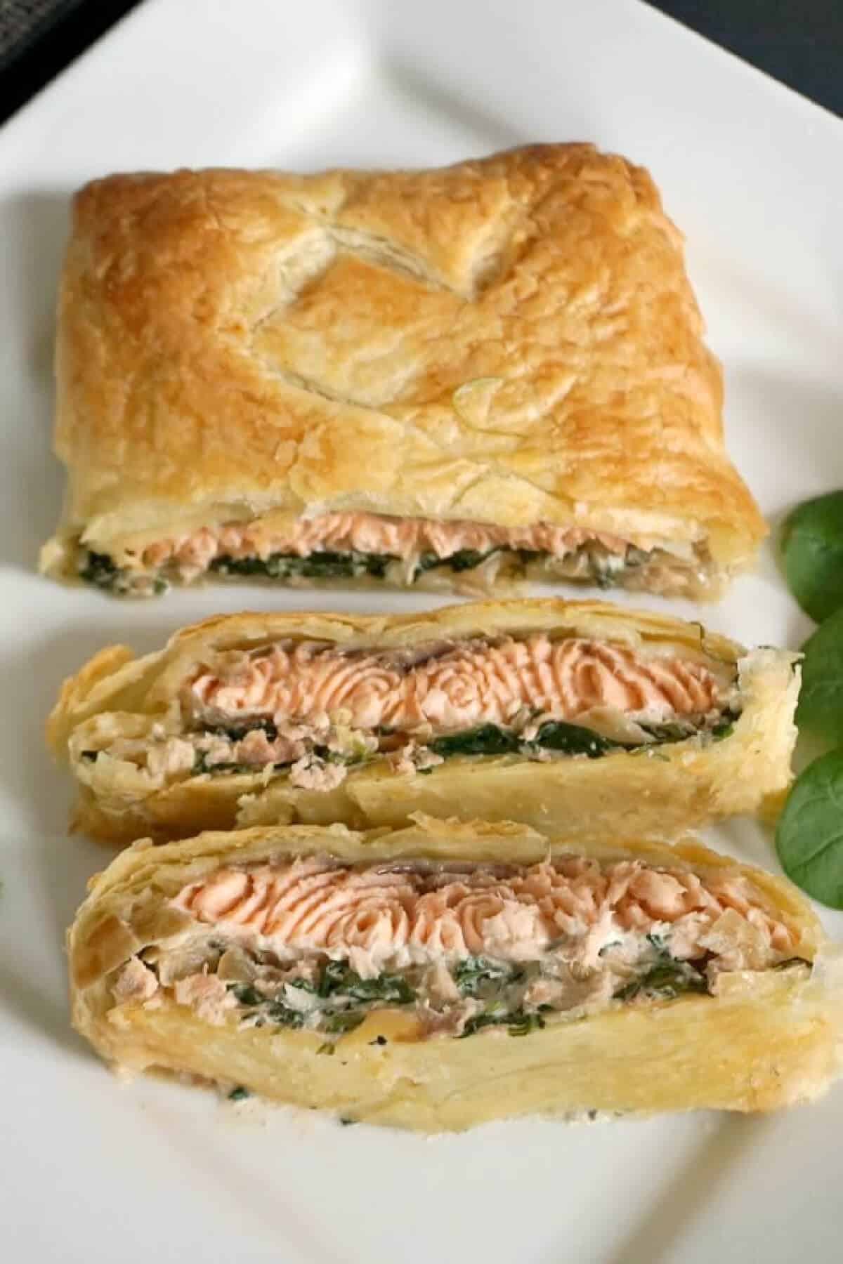 A salmon wellington with 2 slices cut out of it.