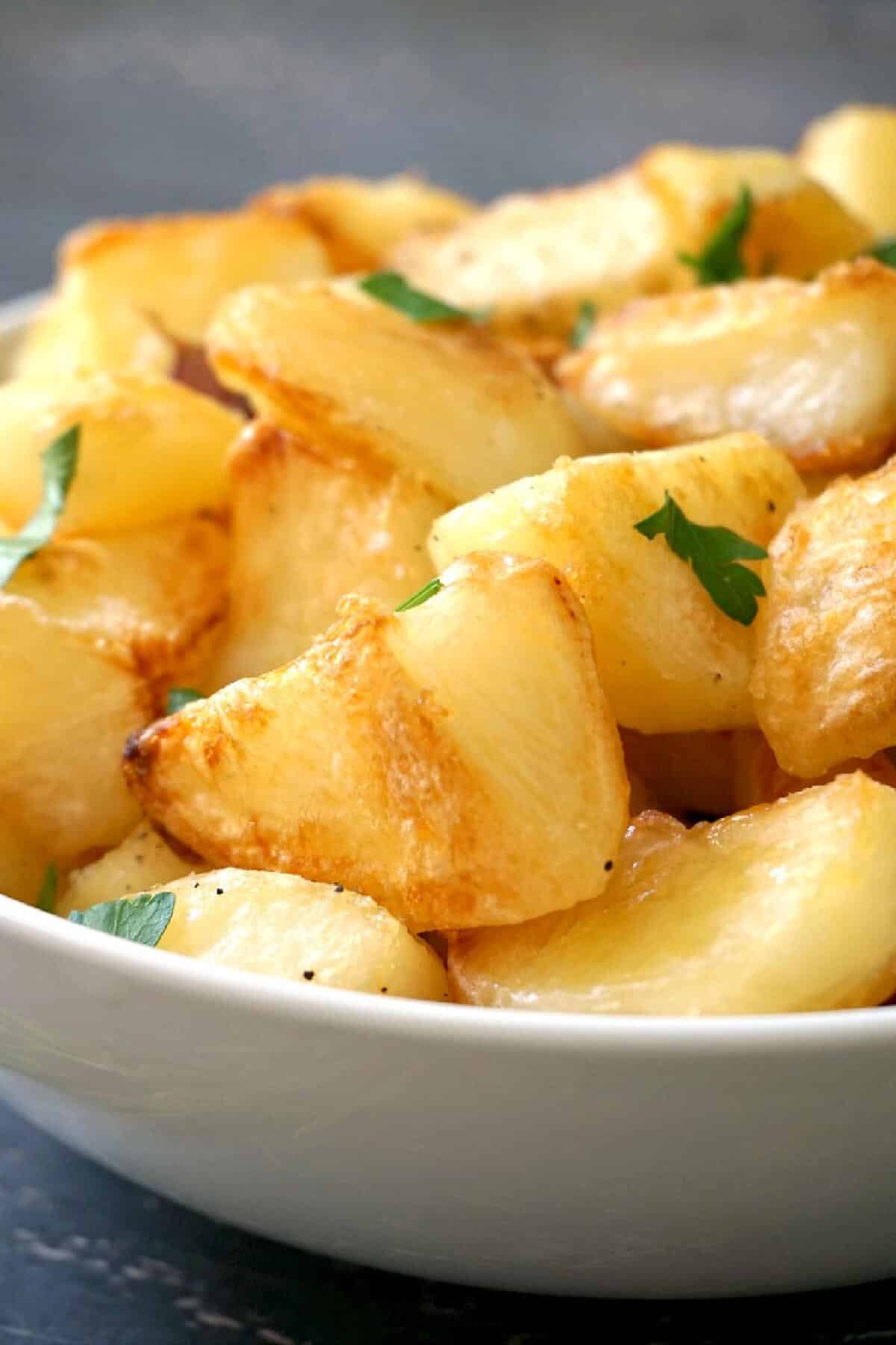 A white bowl with roasted potatoes.