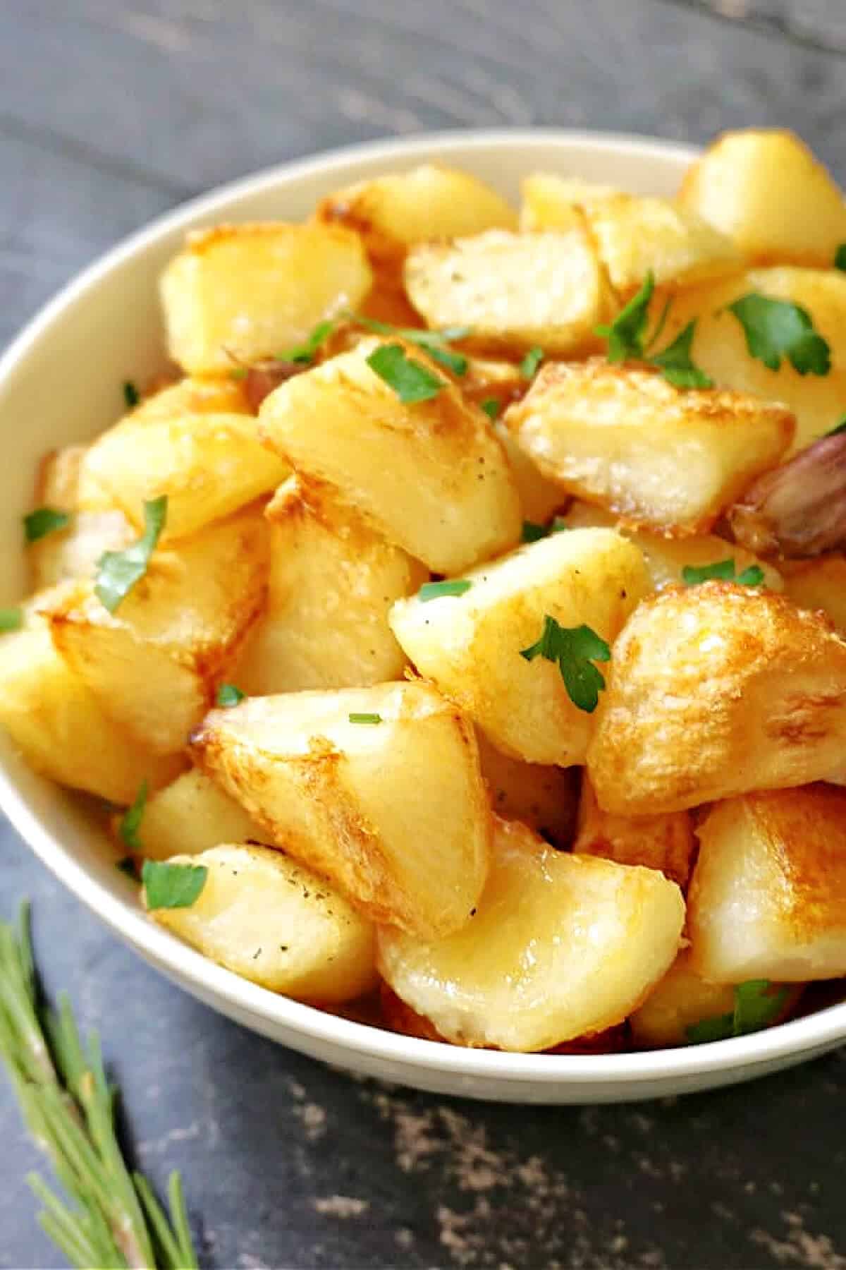A white bowl with roast potatoes.