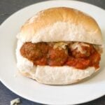 A white plate with a meatball slider on it