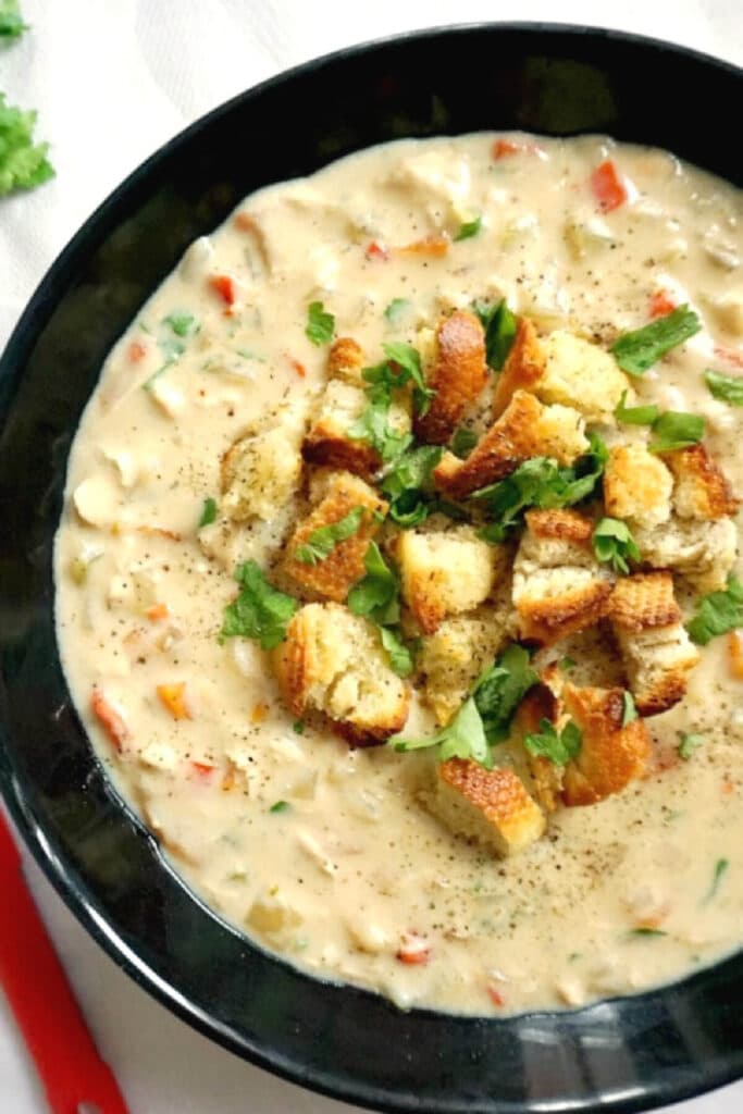 A black bowl with creamy chicken soup