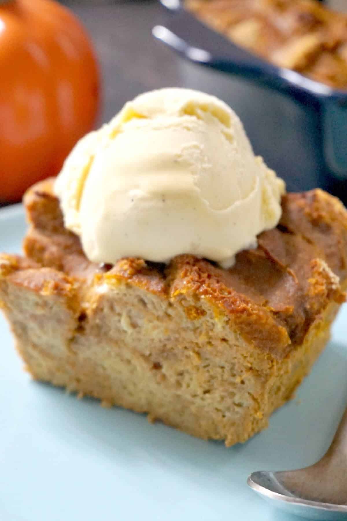 A slice of pumpkin bread pudding topped with a scoop of ice cream.