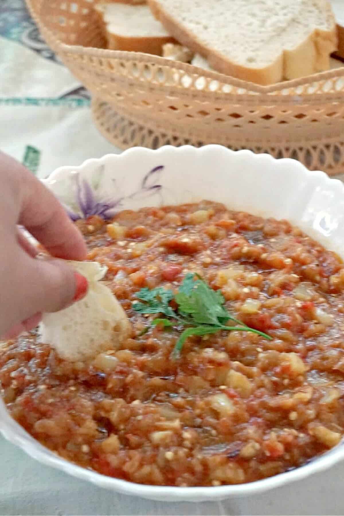 Bread being dipped in an aubergine dip.