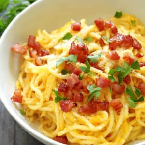 A white bowl with spaghetti carbonara with butternut squash and pancetta
