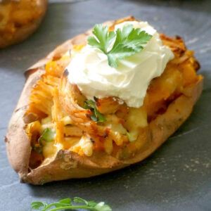 A sweet potato topped with a dollop of yogurt and parsley