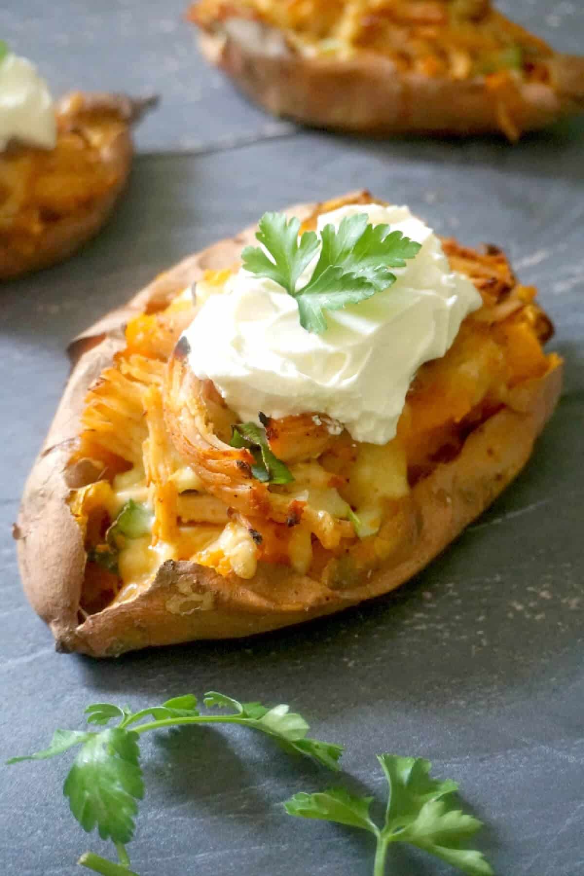 A sweet potato topped with a dollop of yogurt and parsley.