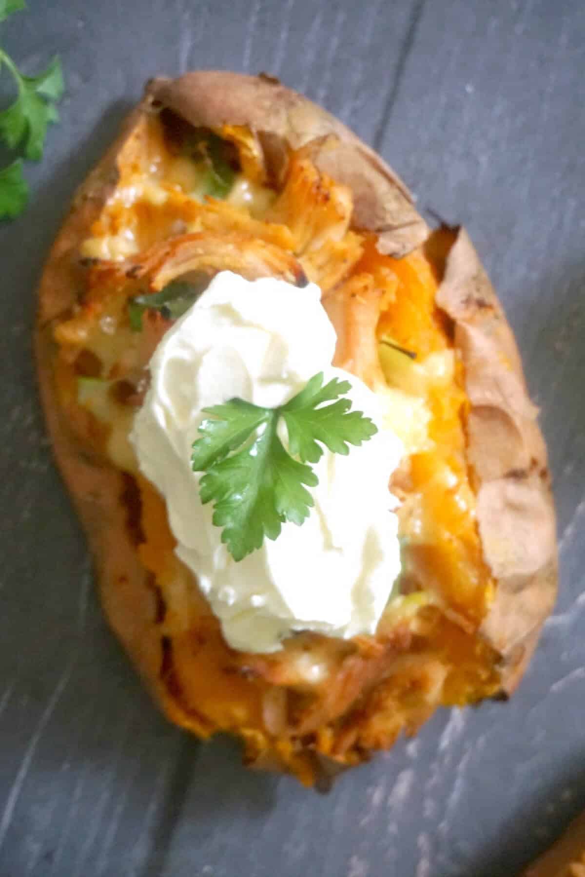A sweet potato topped with yogurt and parsley.
