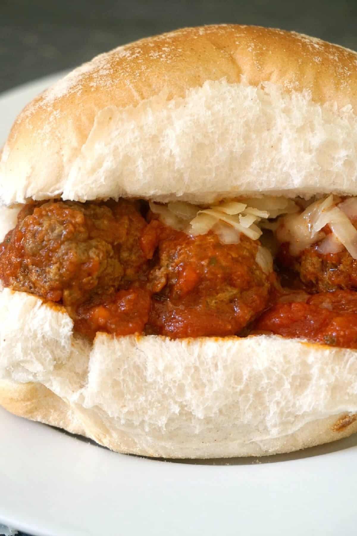 A meatball slider on a white plate.
