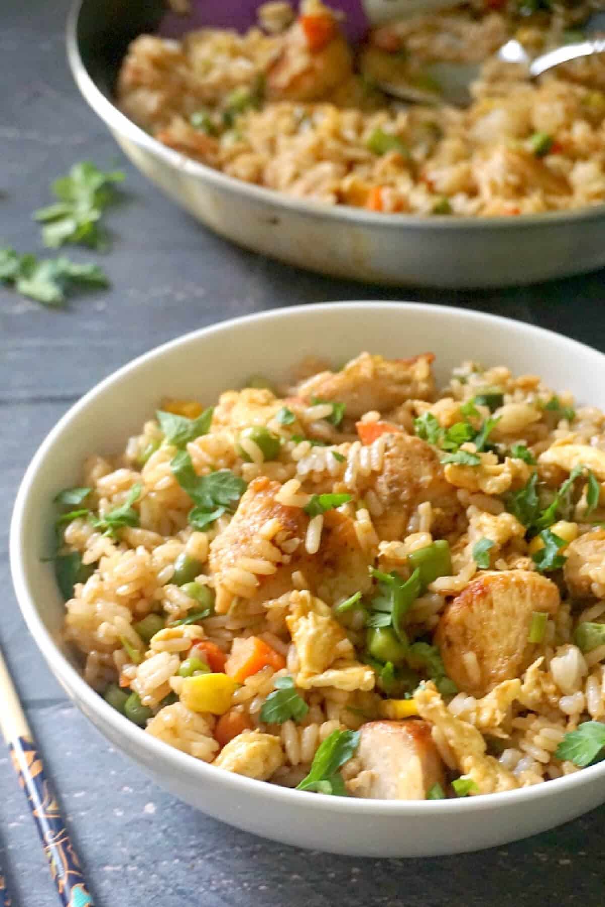A white bowl with egg fried rice with chicken.