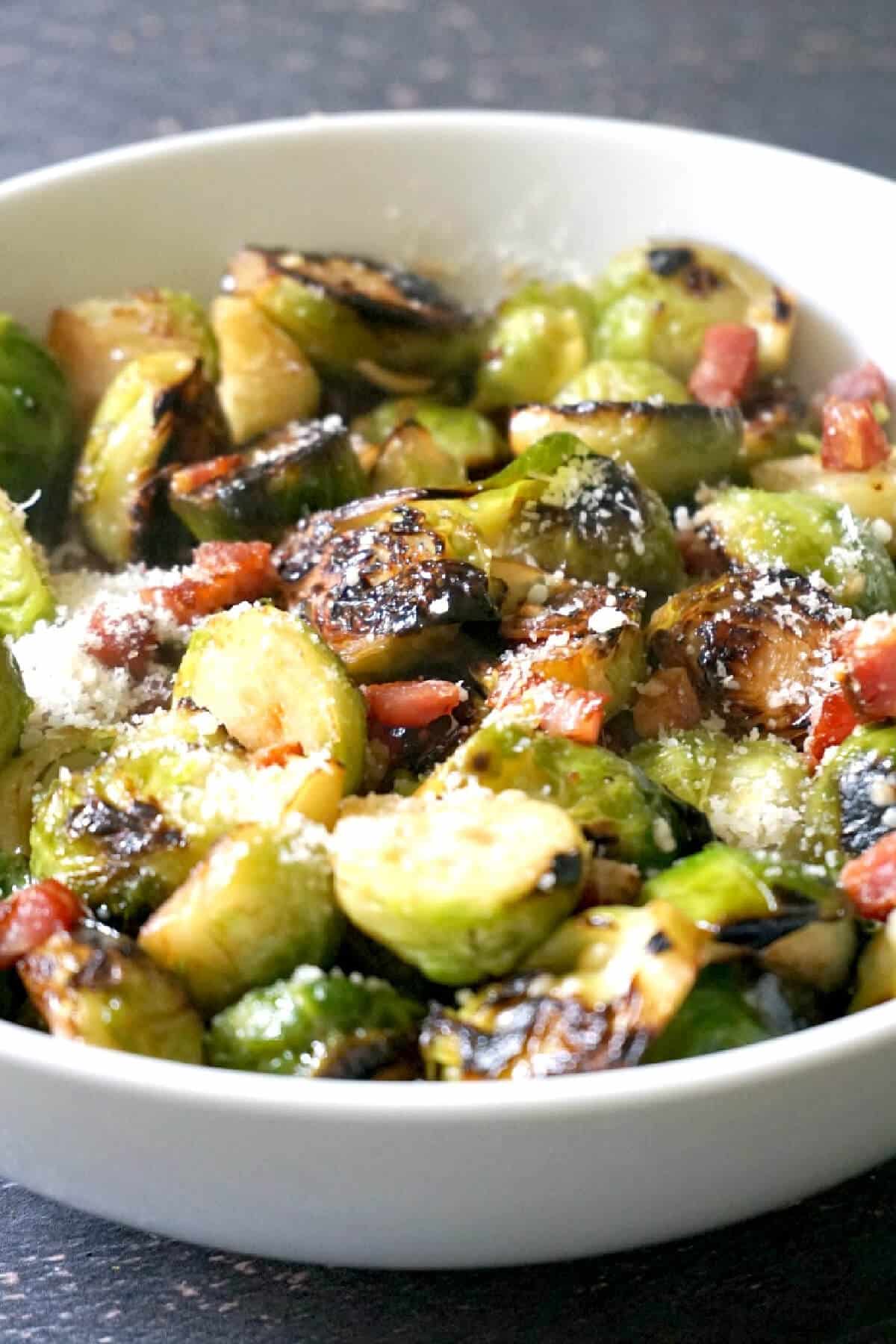 A white bowl with brussels sprouts and bacon.