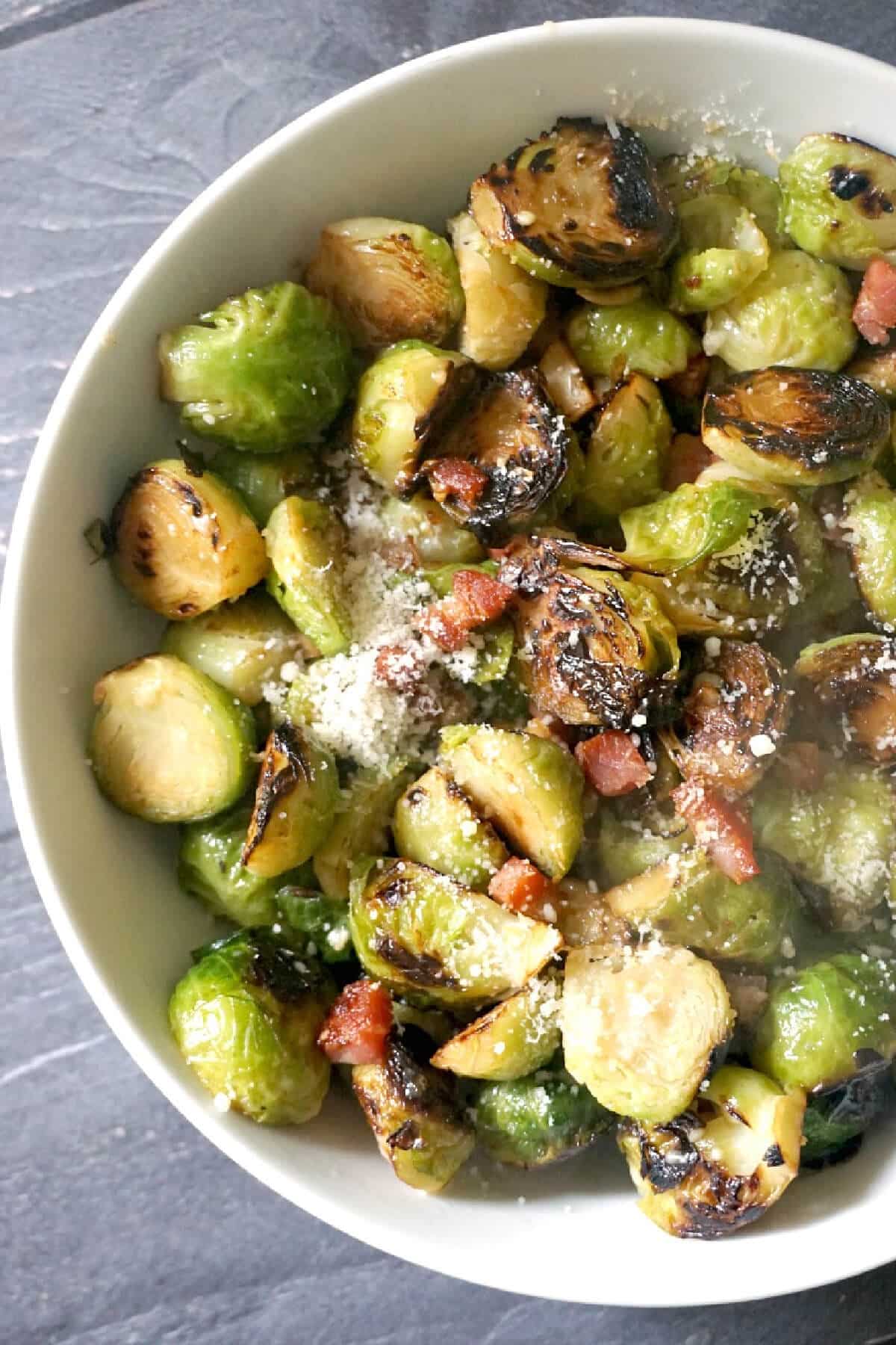 A white bowl with brussels sprouts and bacon.