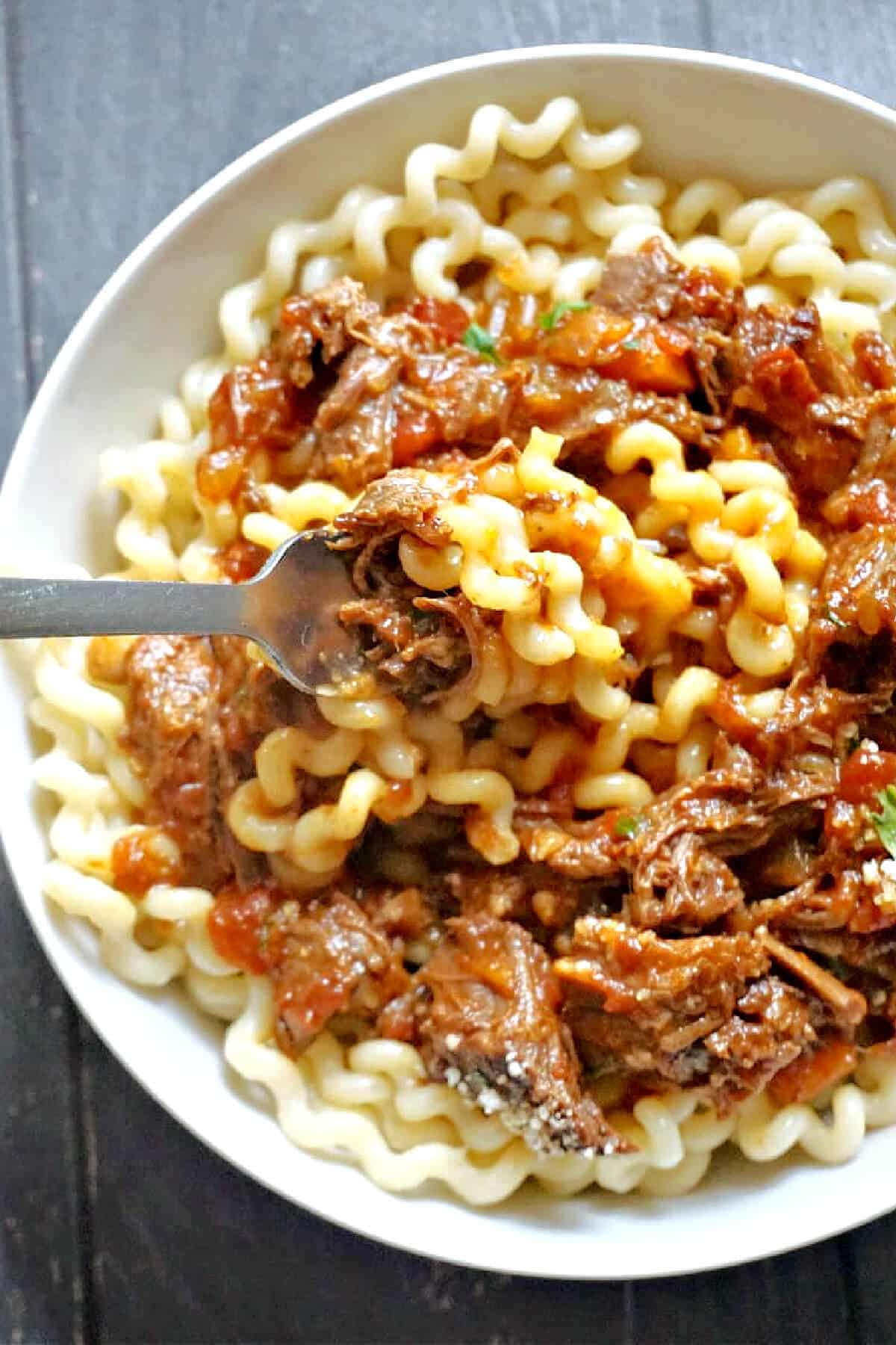 A white plate with pasta and beef sauce.
