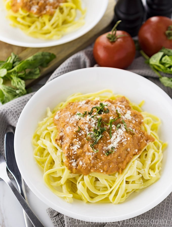 A white plate with spaghetti topped with creamy chicken.