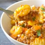 A white bowl with gnocchi bolognese