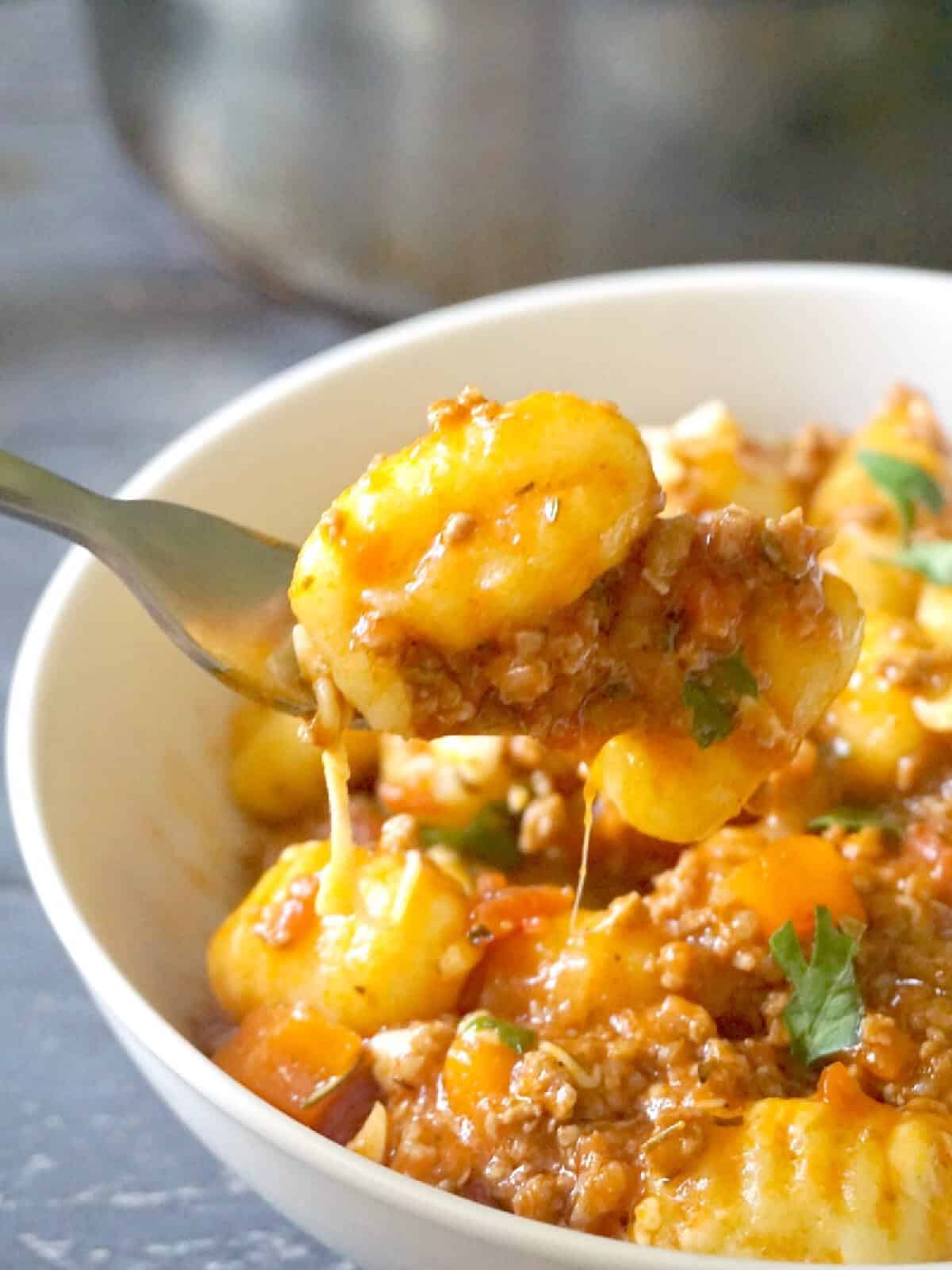 A white bowl with gnocchi in a bolognese sauce.