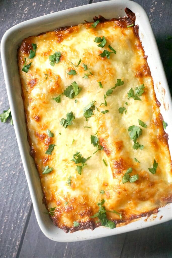 A dish with lasagna and fresh parsley leaves over