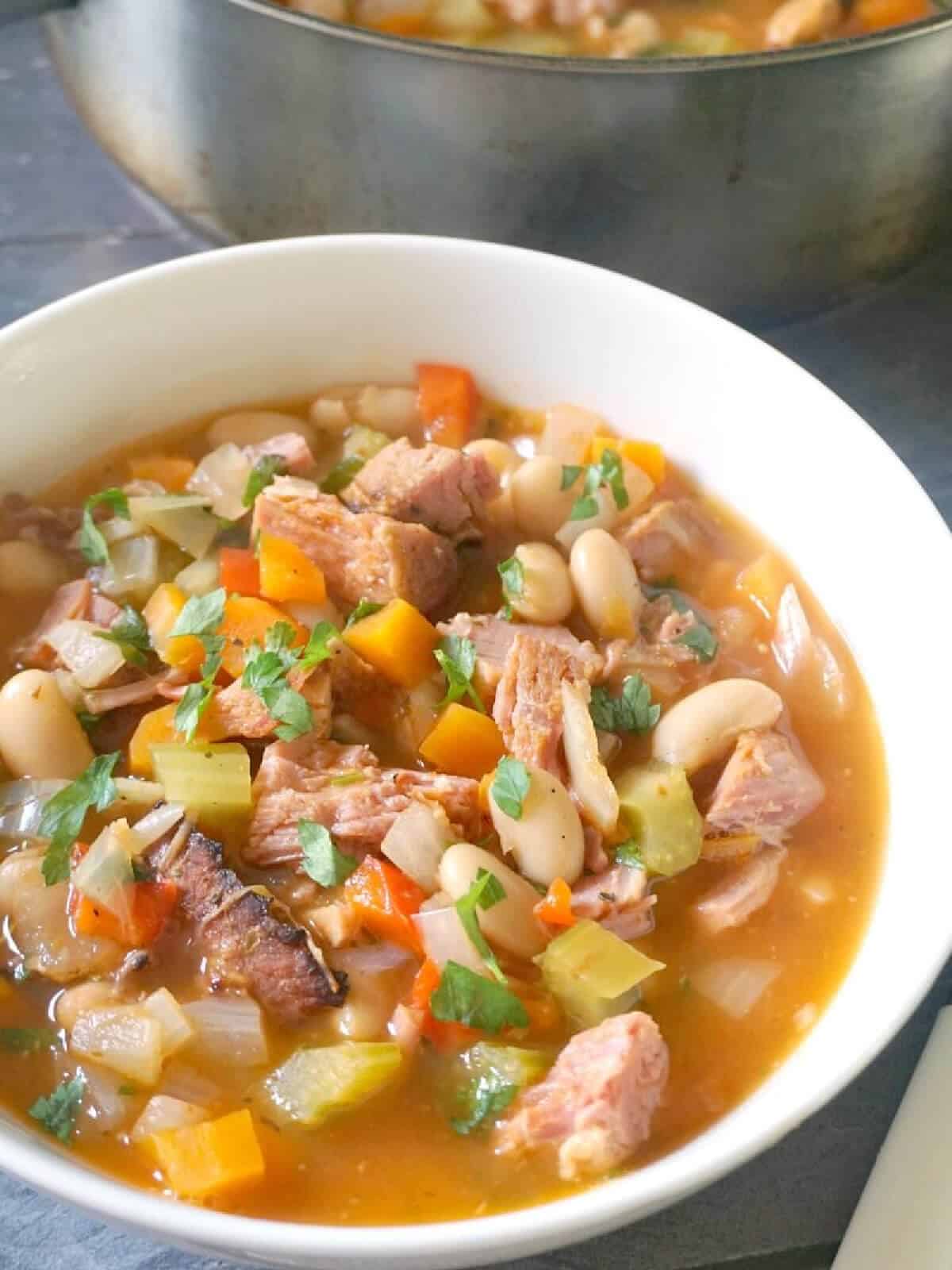 A white bowl with bean and ham soup.