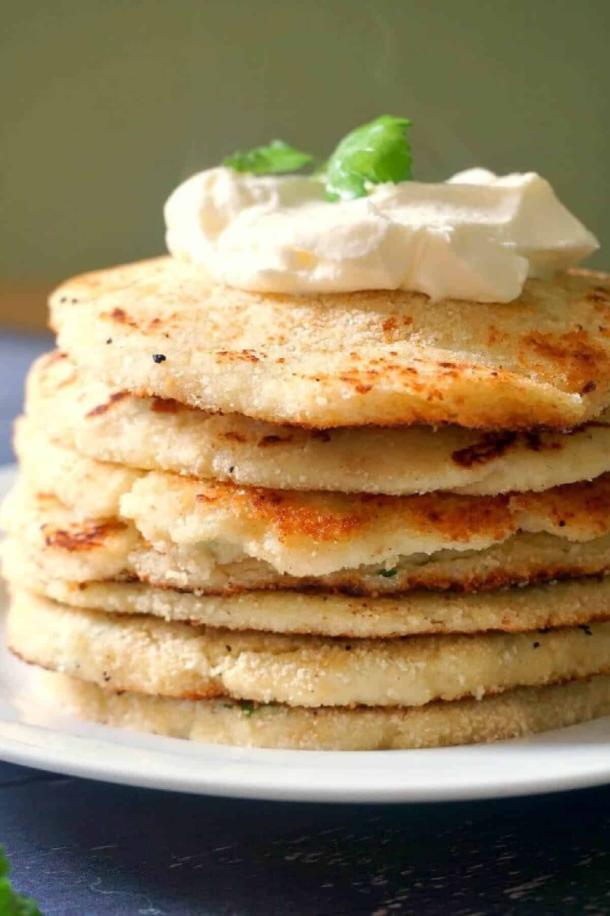 A pile of potato pancakes topped with a dollop of yogurt.
