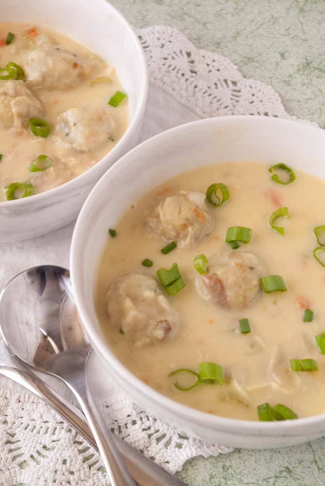 2 white bowls of leftover turkey soup with stuffing dumplings.