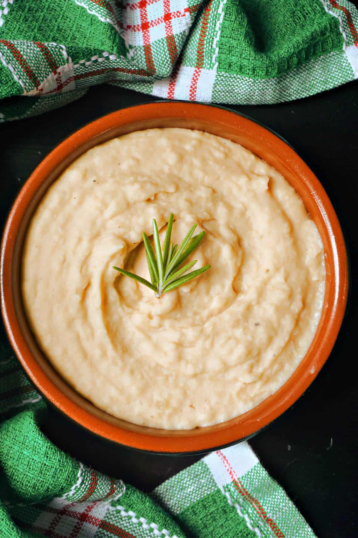 A small bowl with ban mash garnished with a rosemary sprig.