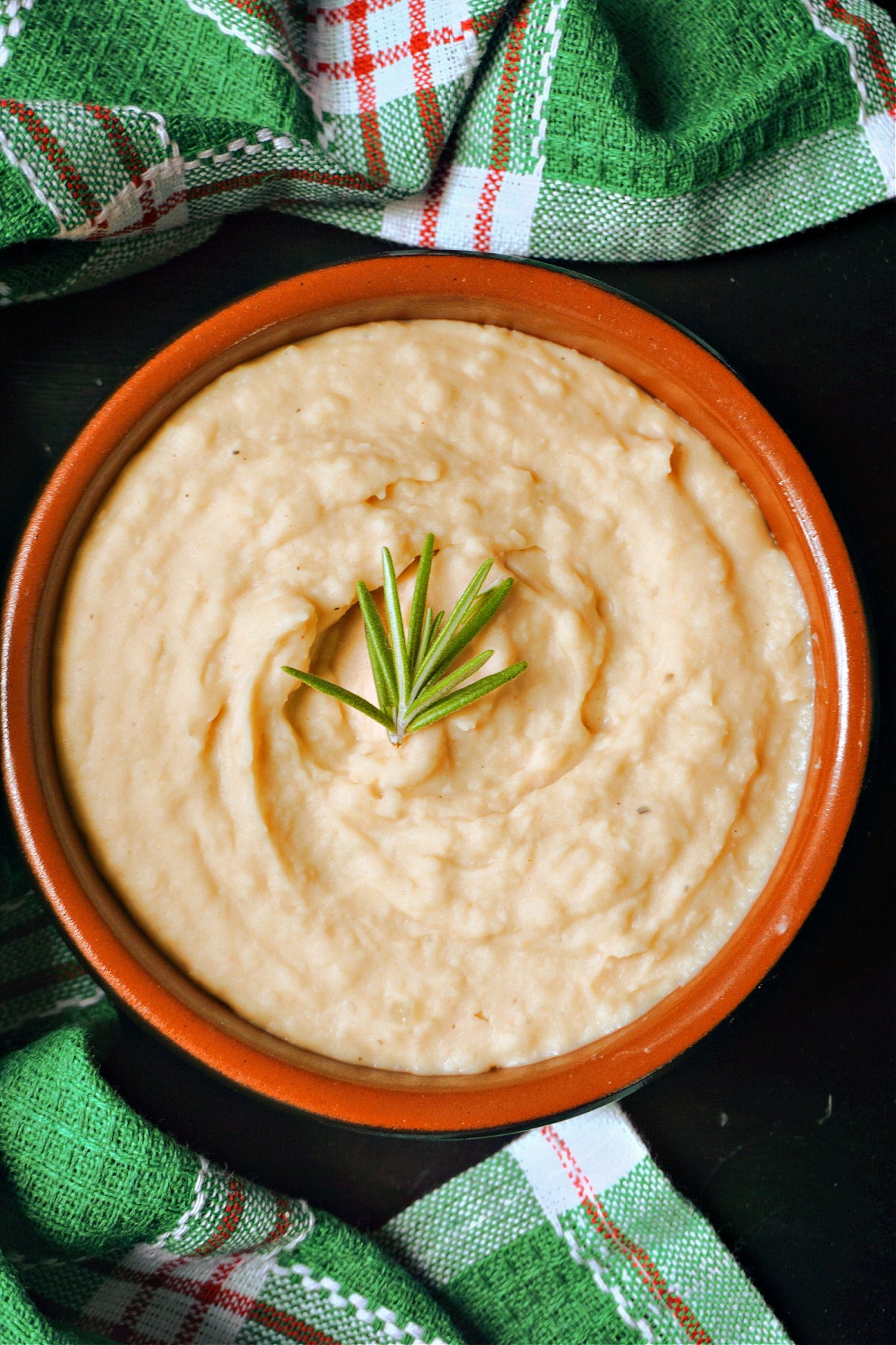 Overhead shoot of a bowl with bean mash garnish with a rosemary sprig