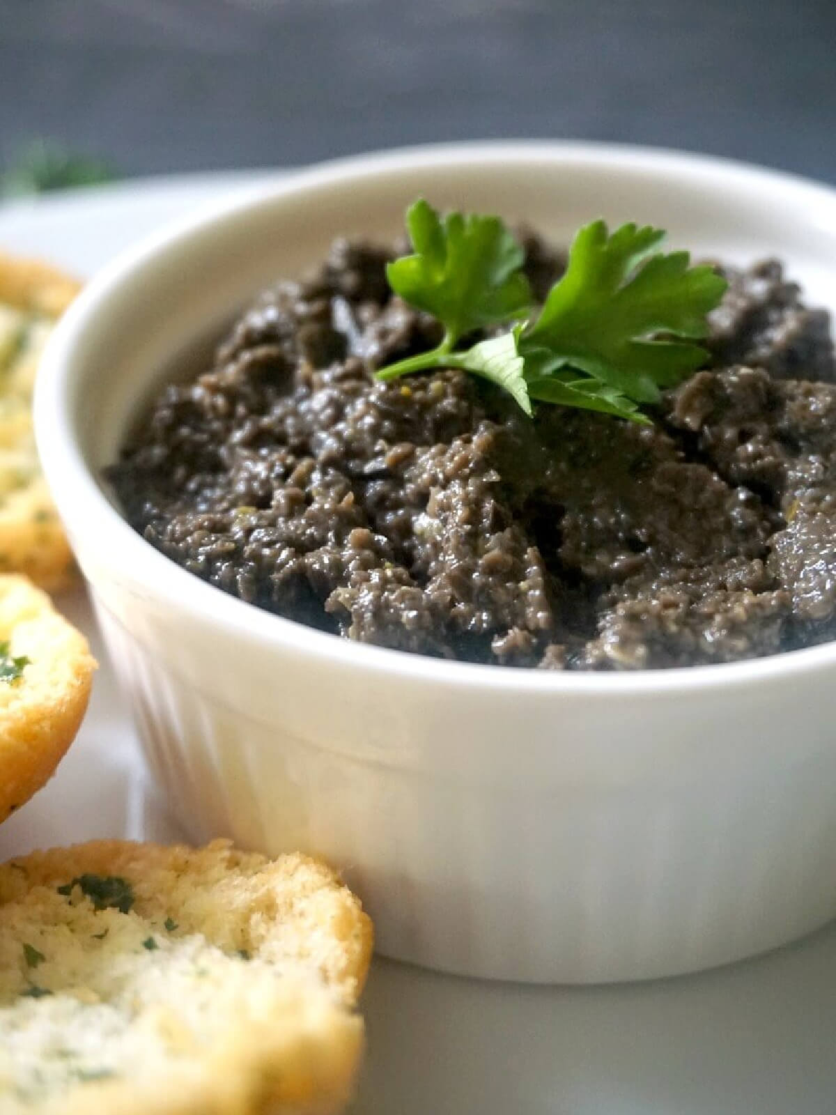 A white ramekin with tapenade.