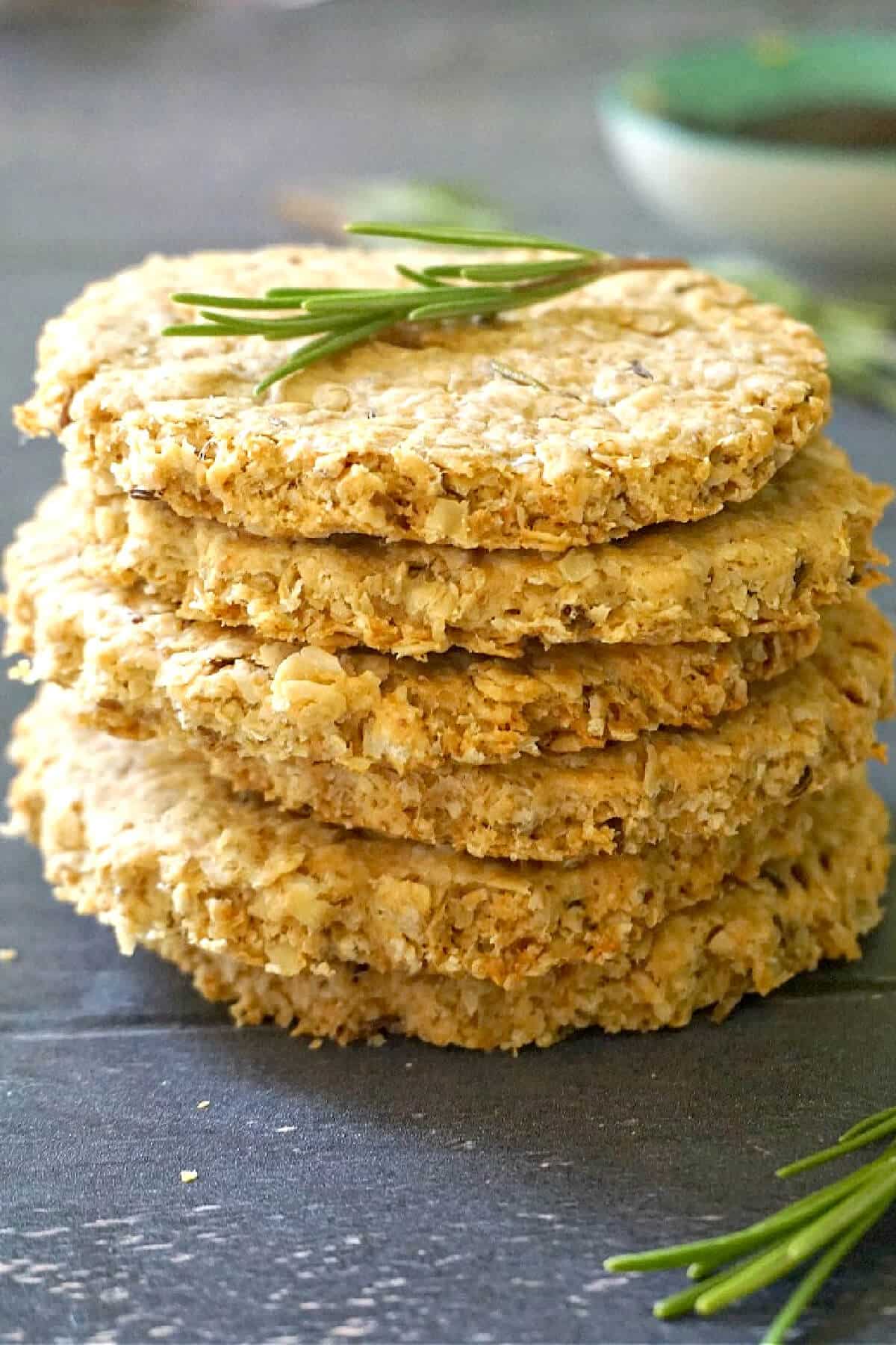 A stack of 6 oat biscuits with a rosemary sprig on top.