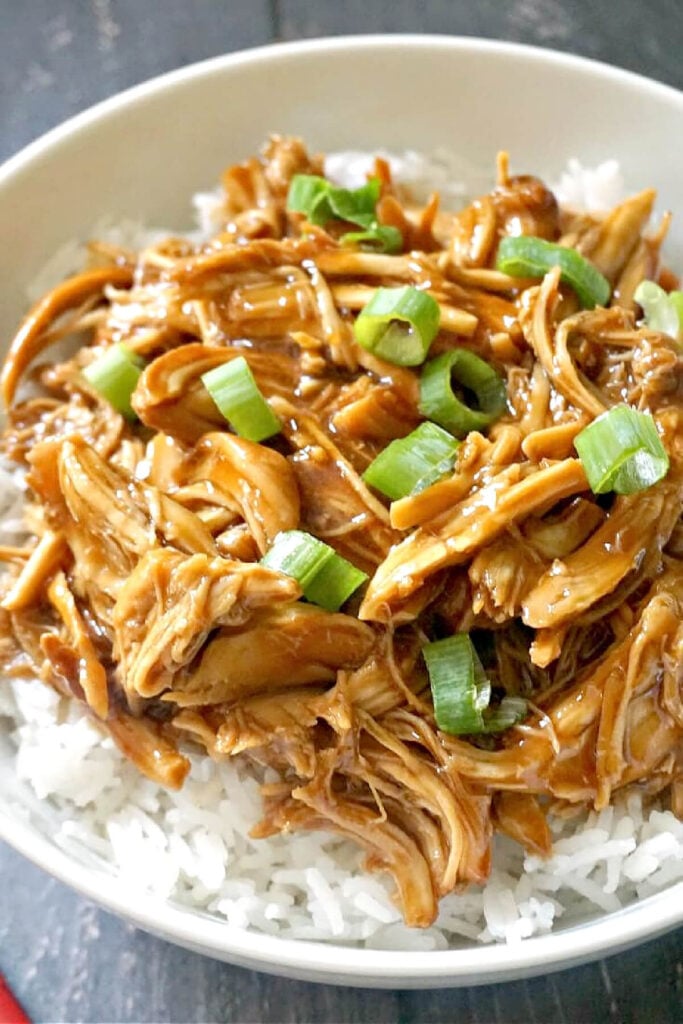 A white bowl with shredded chicken over a bed of rice