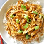 Shredded chicken over a bed of rice in a white bowl