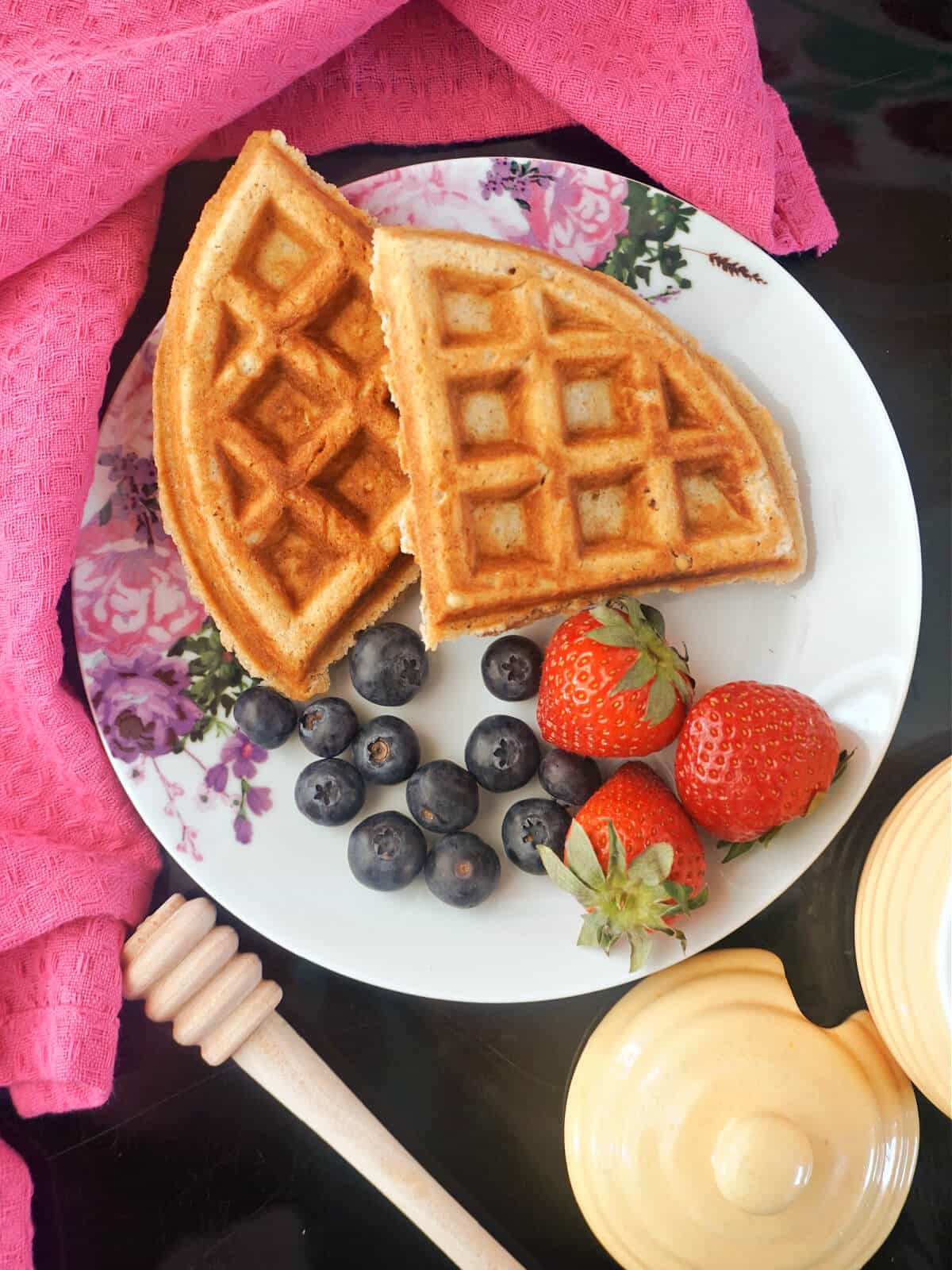 Overhead shoot of a plate with 2 waffles, blueberries and 3 strawberries