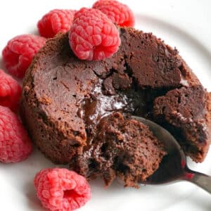 A molten chocolate cake surrounded by raspberries